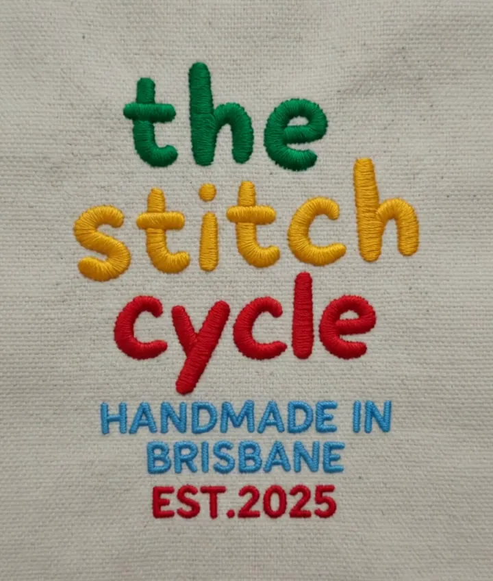 The Stitch Cycle logo embroidered in coloured thread on natural canvas